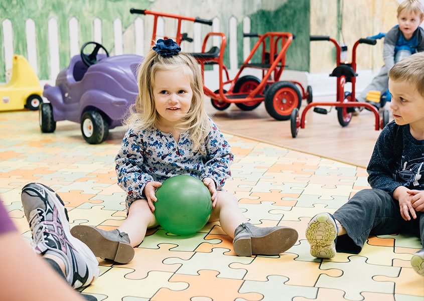 Preschoolers sitting on the floor playing with a ball