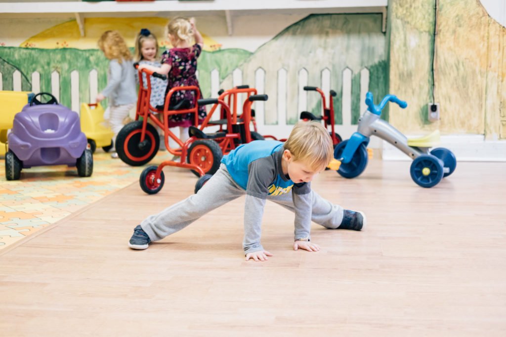Little boy doing a split in classroom.