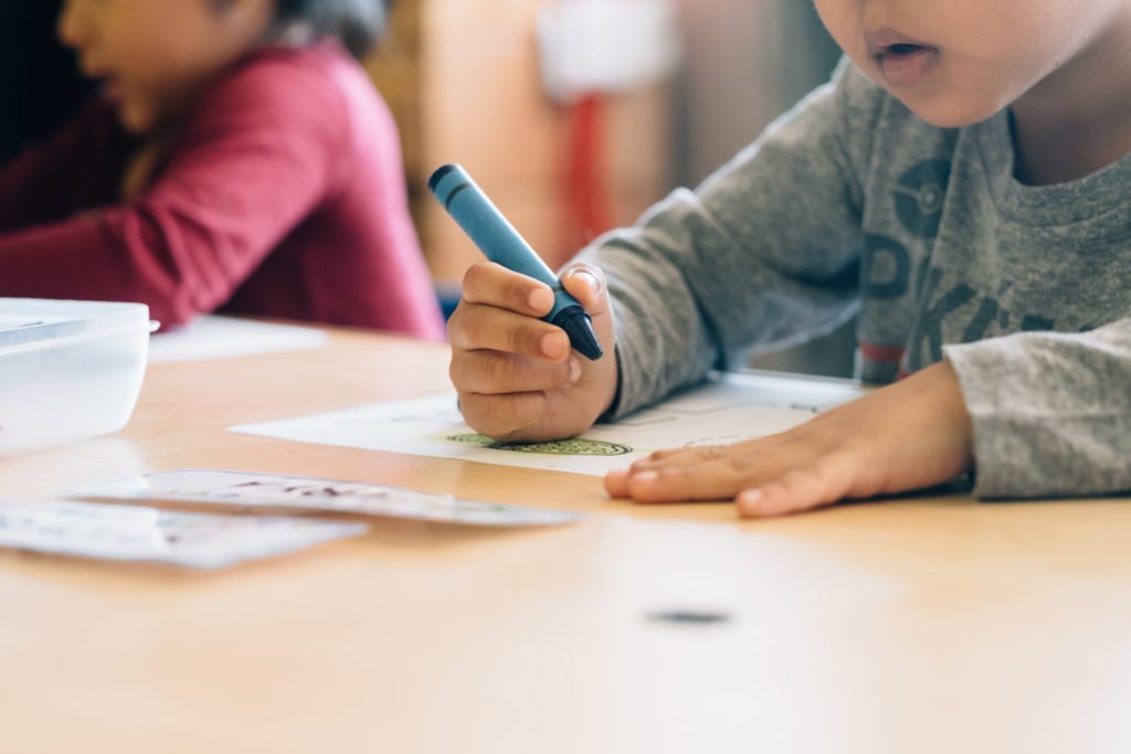 Image: Two young children sitting at a desk.