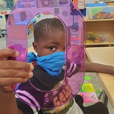 A boy wearing a mask looks through the hole in a toy