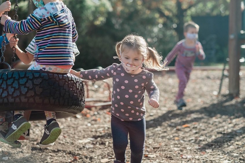 Image: A young child plays with other children outside through their child care program.