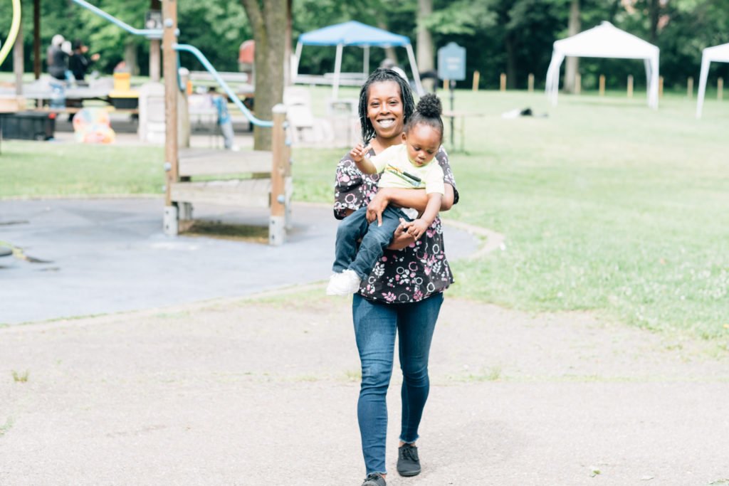 Women smiling holding child walking in park | family dynamics