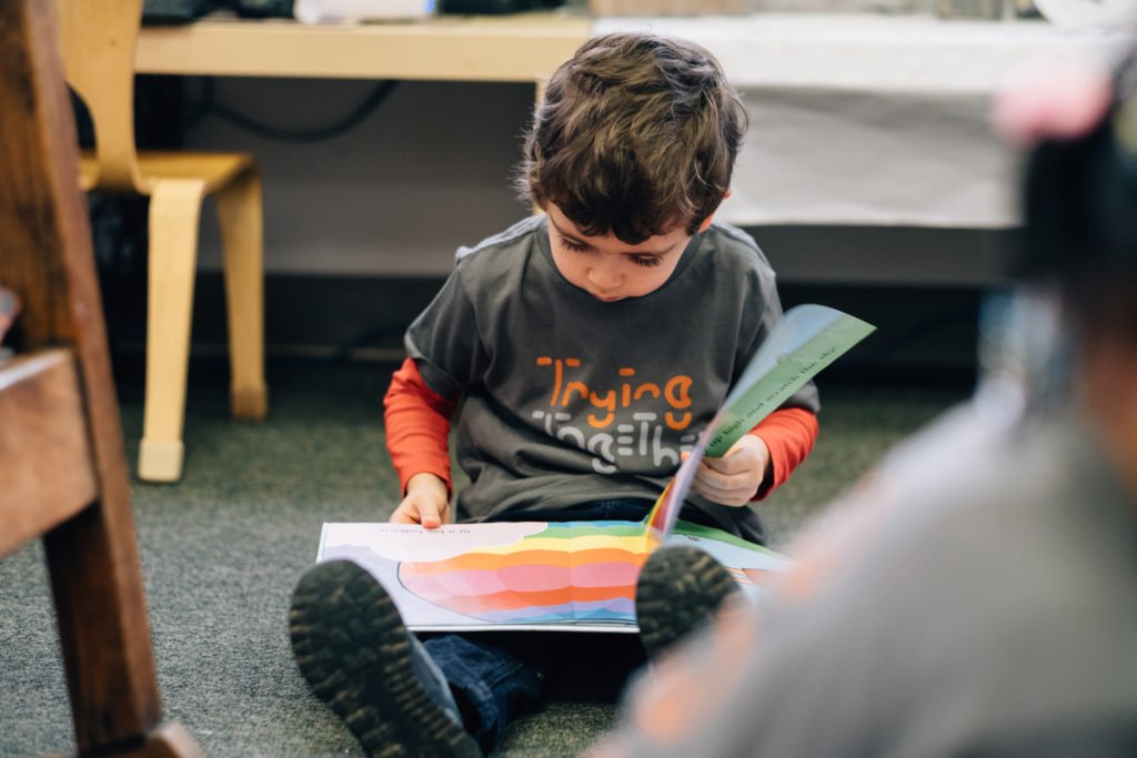 A child sitting on the ground reading a book | gender identity books