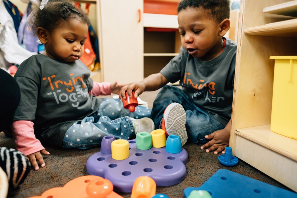 Two children playing on the ground with toys | types of family