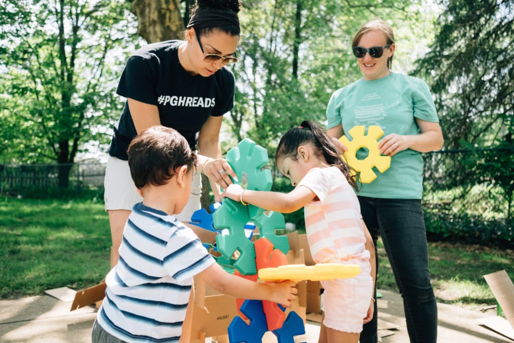 Two young children playing with building blocks with two parents | LGBTQ+ family