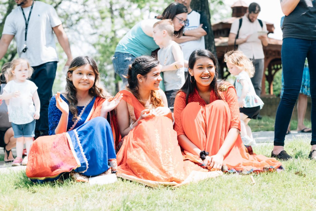Three girls in sari dresses sit on the grass | defining family dynamics