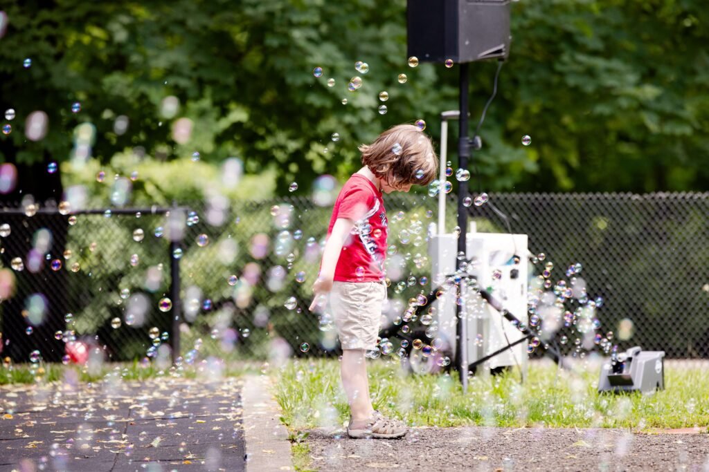 Child standing in looking down with bubble floating them around | Play is Crucial for Brain Development