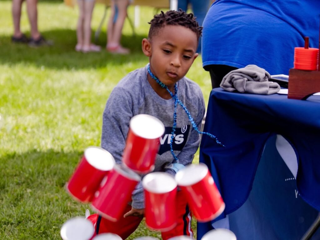A young boy throwing a ball knocking over red cans | How Play Can Help Children Alleviate Toxic Stress