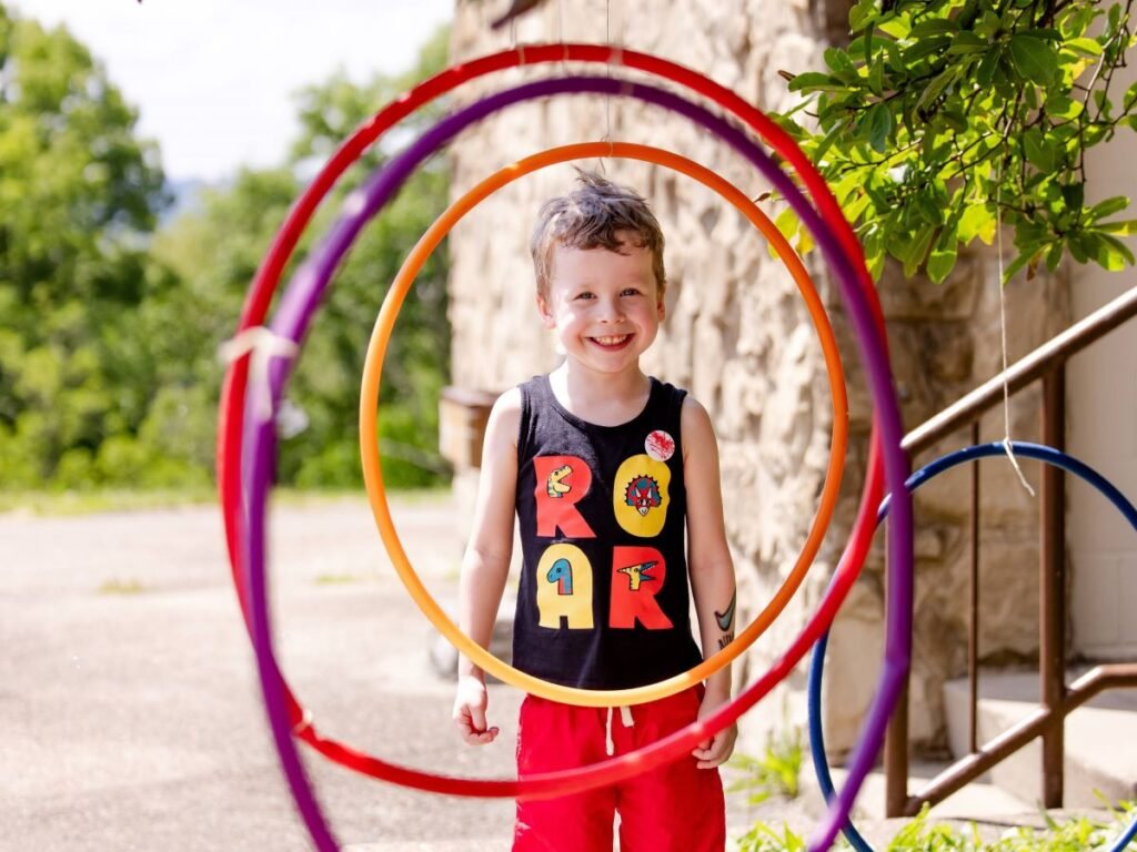 A young bar standing on the other side of four hula hoops smiling | The Need for Pretend Play in Child Development