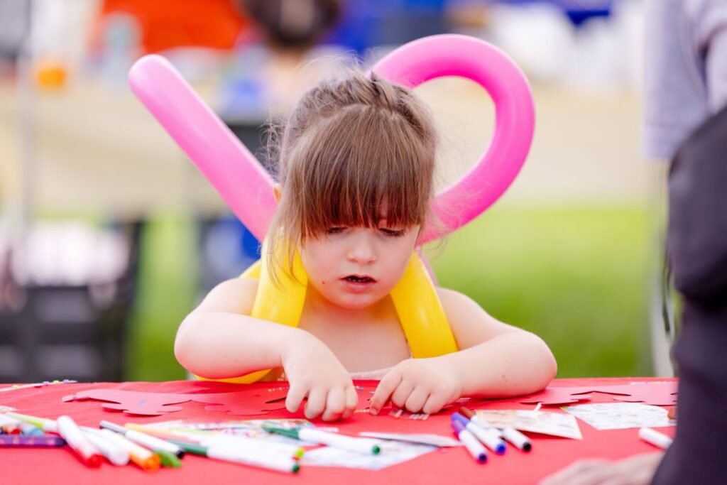 A young girl standing at a table working on a craft | Thinking and Play