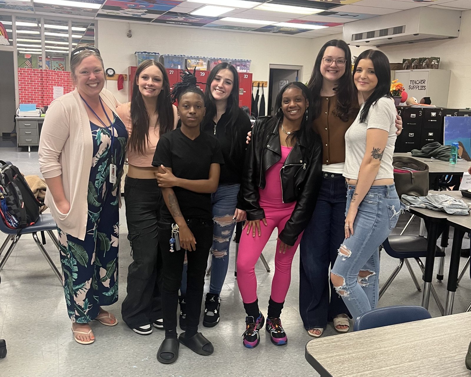 A group of high school students pose together in a classroom